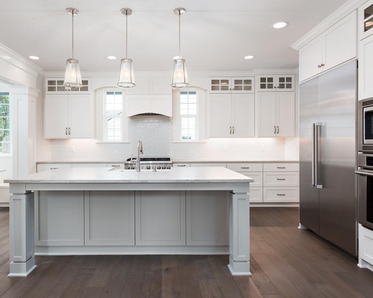 beautiful kitchen in new luxury home with island, pendant lights, and hardwood floors